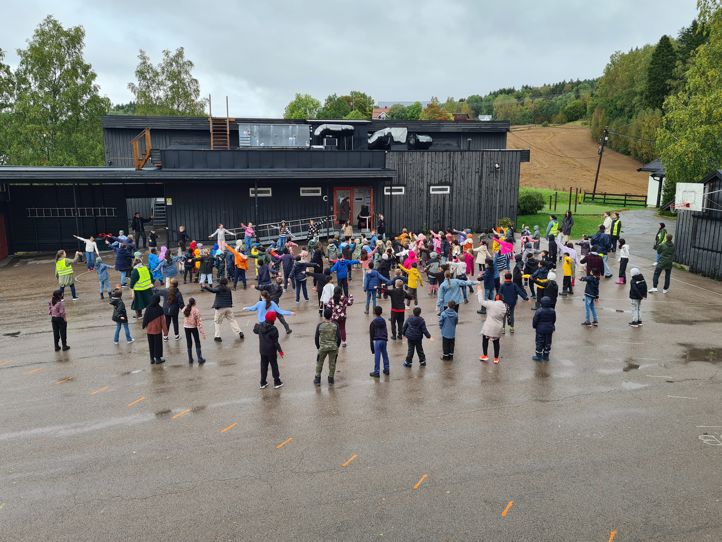 Elever og lærere danser Blime-dansen i skolegården