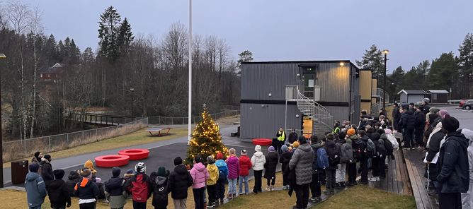Foto: Elever og ansatte står samlet i amfiet rundt nytent juletre Elever og ansatte står samlet i amfiet rundt nytent juletre