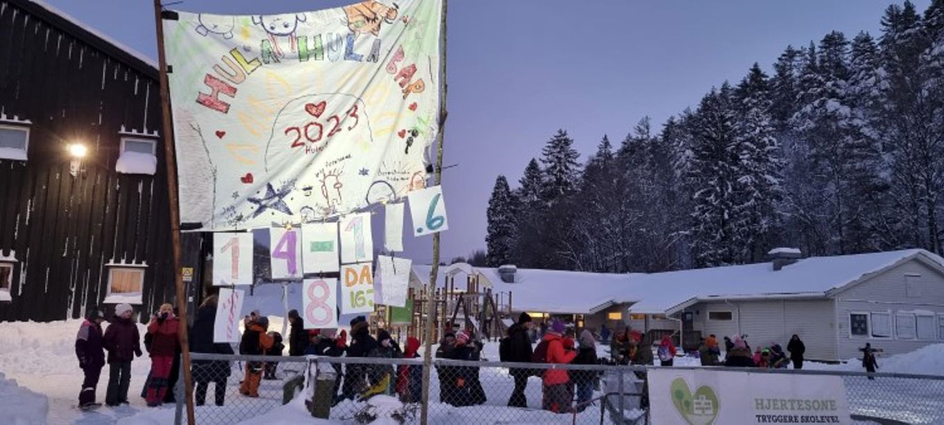En gruppe mennesker i skolegården og får servert varm toddy