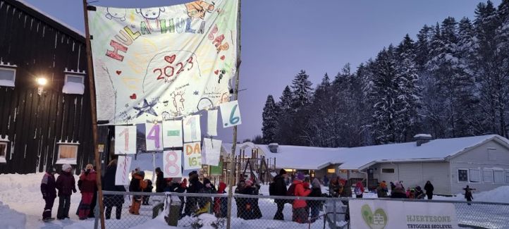 En gruppe mennesker i skolegården og får servert varm toddy