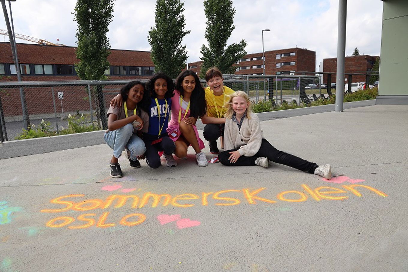 Elever som sitter på i skolegården til en skole som har Sommerskoletilbud