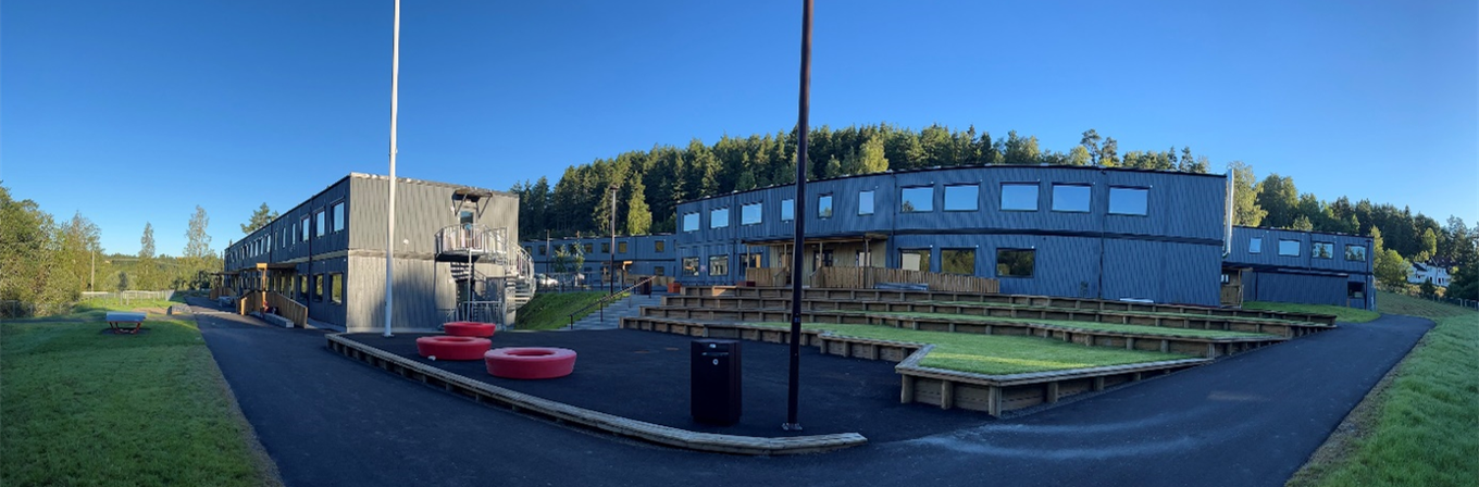 En bygning med et amfi og en flaggstang foran, midlertidige Klemetsrud skole