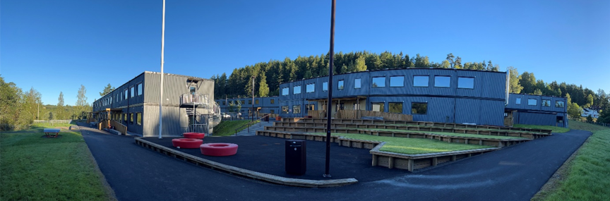 Foto: Amfiet i skolegården En bygning med et amfi og en flaggstang foran, midlertidige Klemetsrud skole