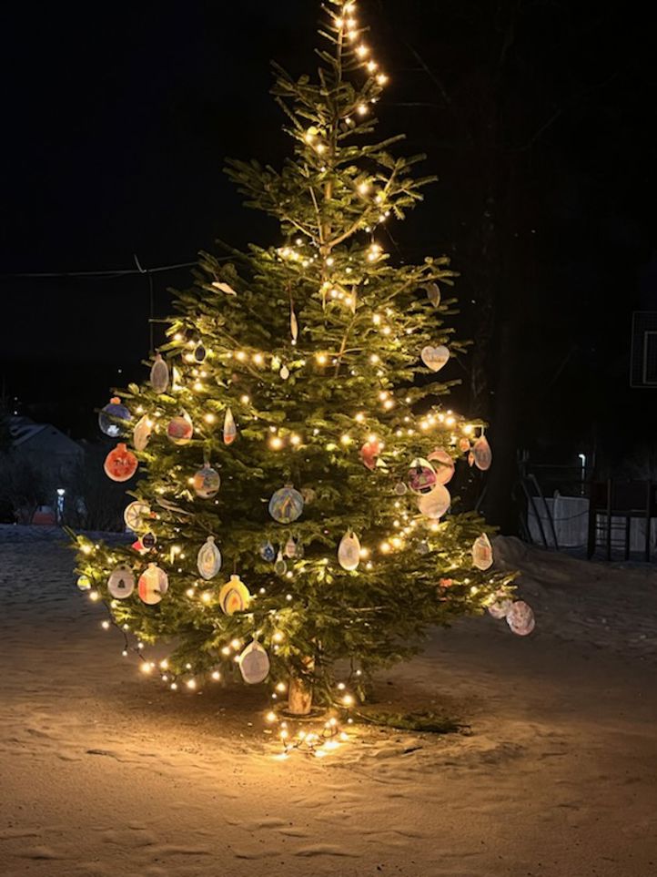 Skolens juletre pyntet med lys og elevenes egenproduserte ornamenter