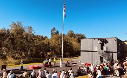 Foto: Foresatte og skolestartere som sitter på amfiet foran en flaggstang Foresatte og skolestartere som sitter på amfiet foran en flaggstang